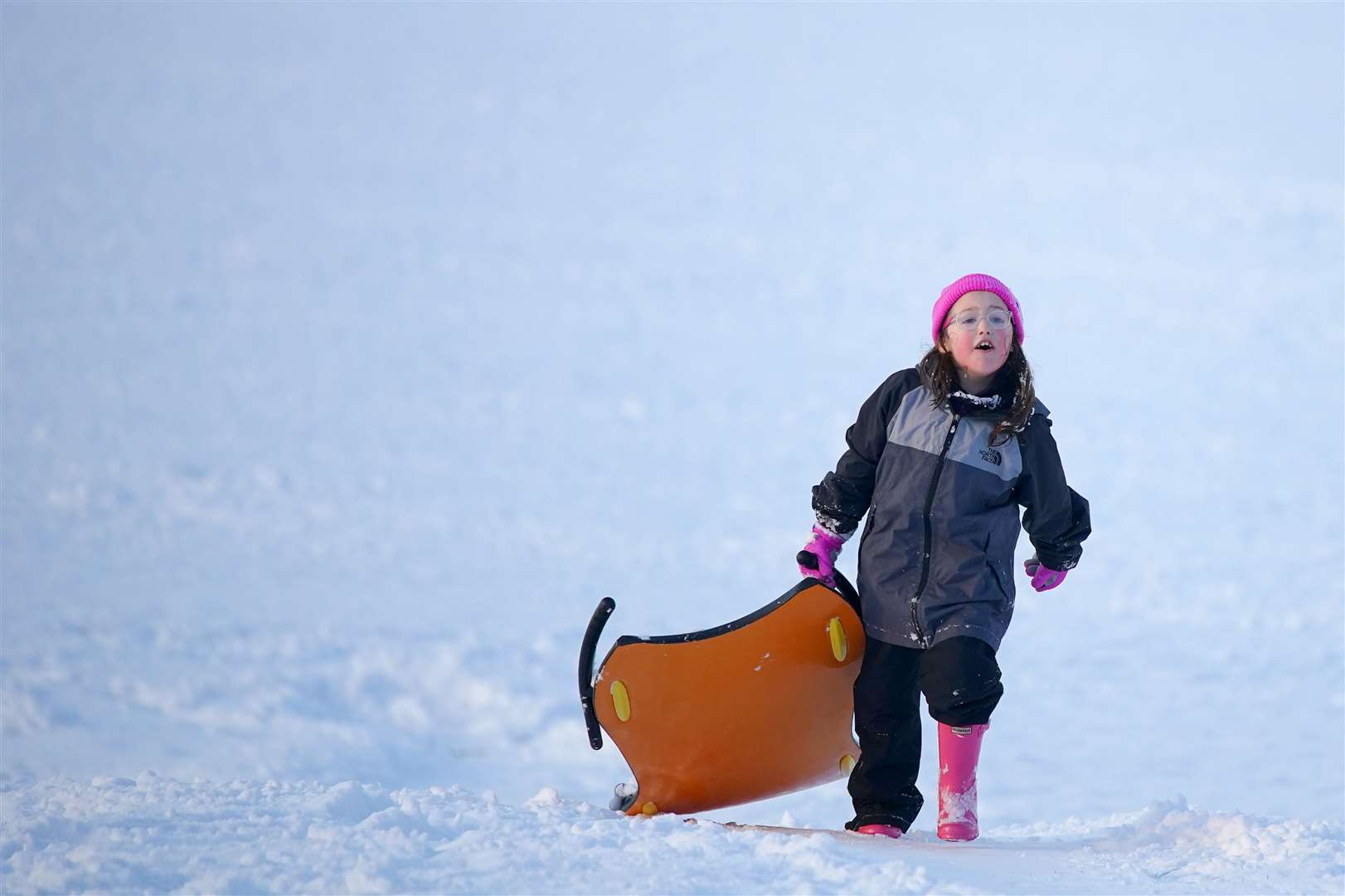 A young girl takes her sledge outside for fun in the snow (Peter Byrne/PA)